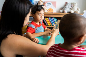 Adult helps child read in a classroom