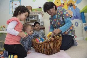 Educator helps children choose toys from a bin