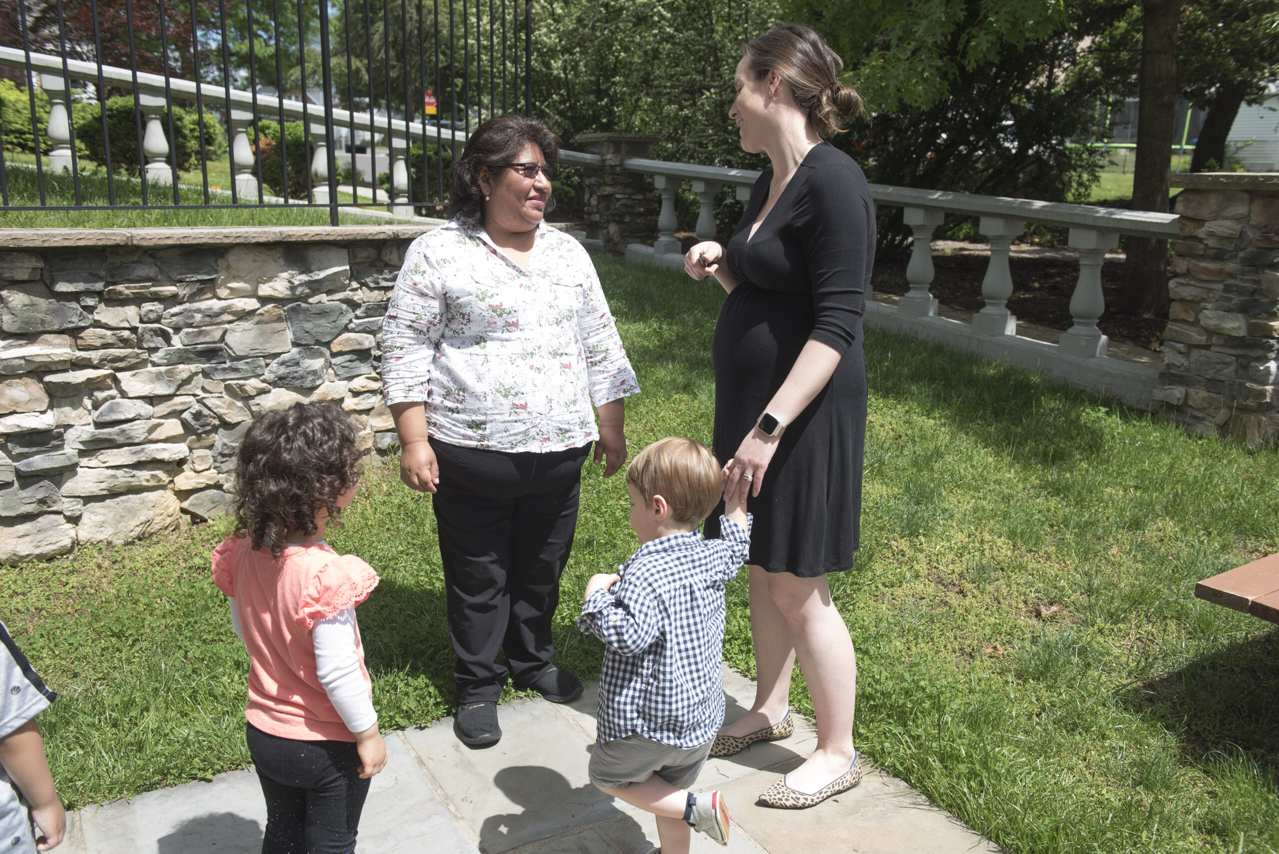 Two adults with children talk outside