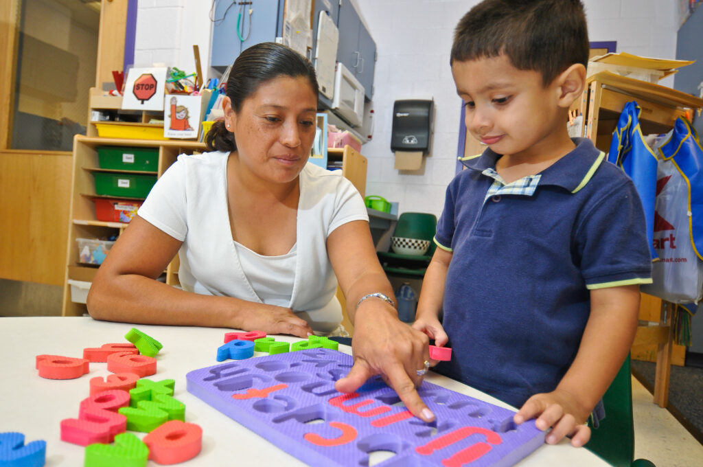 Teacher helps child with an alphabet game