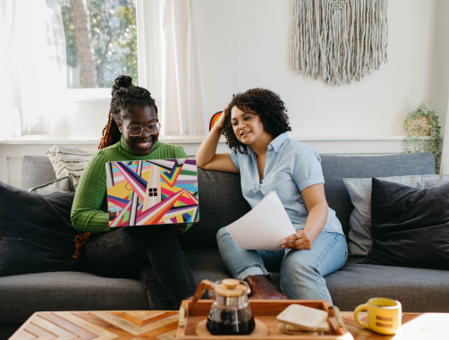 Adults looking at a laptop while sitting on a couch