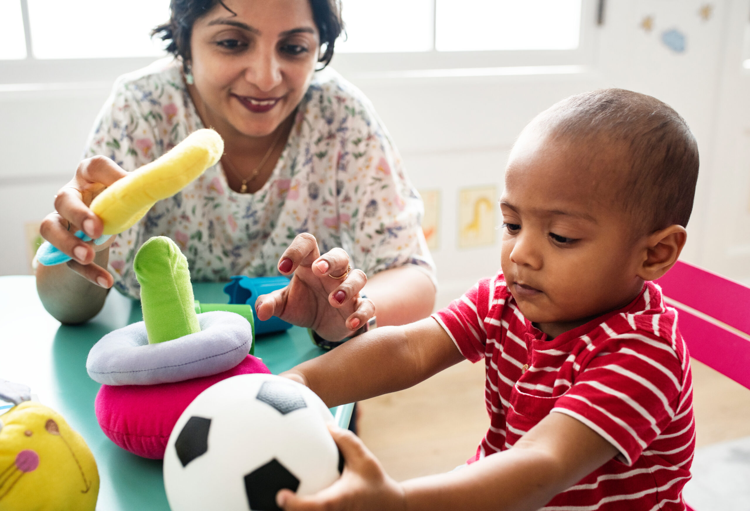 Nursery child playing with teacher in the classroom